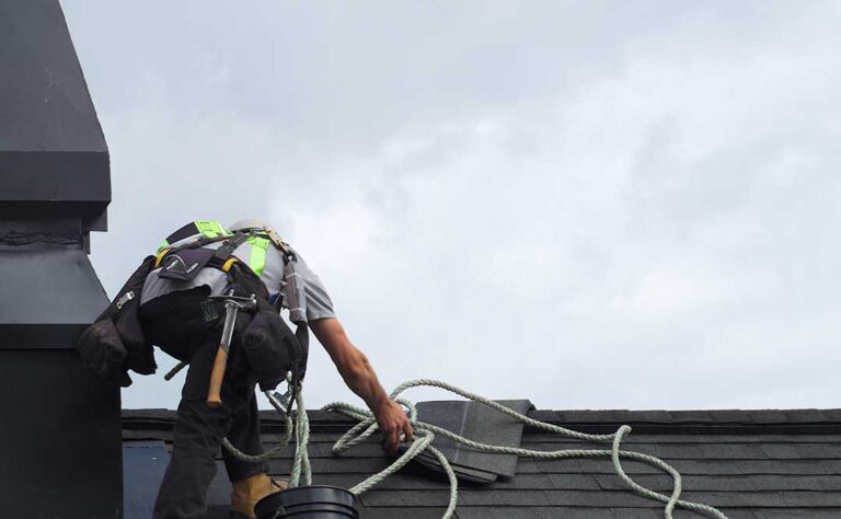 Roof inspector examining uneven shingles and exposed flashing on a residential roof.