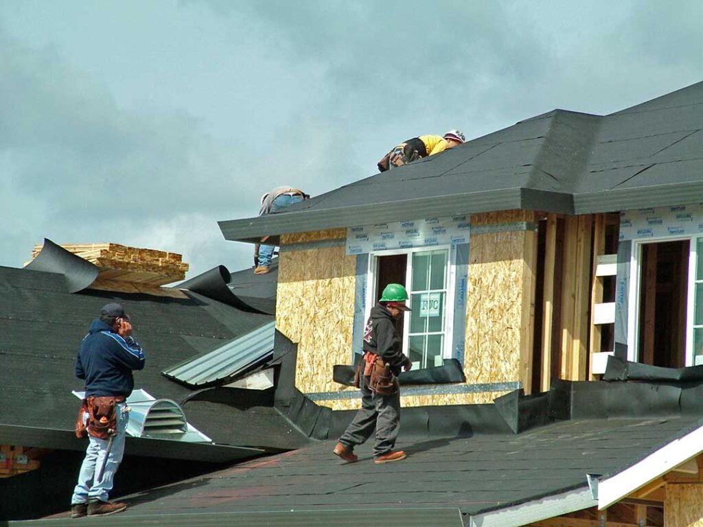 Homeowner inspecting roof shingles with binoculars beside a ladder, gloves, flashlight, and gutter scoop.