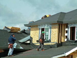 Homeowner inspecting roof shingles with binoculars beside a ladder, gloves, flashlight, and gutter scoop.